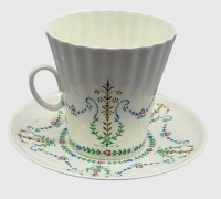 Auktion 374<br>Kaffeetasse und Untertasse von Leningradsker Porzellanmanufaktur Lomonossow (LFZ), UdSSR,  seltenes Dekor: Gerippte beziehungsweise geflutete Form mit klassizistischem, mehrfarbigem Girlanden- und Ranken-Dekor sowie feiner Goldakzentuierung