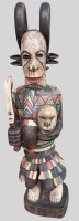 Auktion 375<br>Ikenga-Figur der Igbo  (Nigeria) aus Holz, mit sch&auml;delartigem Gesicht und geh&ouml;rntem Hut, h&auml;lt in der rechten Hand ein gebogenes Schwert und in der linken einen menschlichen Kopf; bunt bemalt. H-115 cm, 20 kg