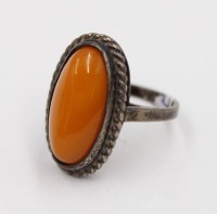 Auktion 376<br>antiker Silberring mit einem l&auml;nglichen Butterscotch-Bernstein-Cabochon in einer kordelartig gefassten Fassung.