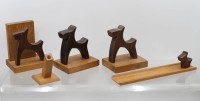 Auktion 376<br>ein Set aus handgeschnitzten Holzfiguren und Wohnaccessoires im Stil eines Terriers (Mid-Century Folk Art / Art Deco), darunter Buchst&uuml;tzen, einen kleinen Stifte- oder Kerzenhalter, ein l&auml;ngeres Sch&auml;lchen/Ablagebrett und kleine Hunde-Dekorfiguren aus dunklem und hellem Massivholz.
