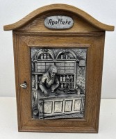 Auktion 376<br>Wandschr&auml;nkchen "Apotheke" beschriftet, mit Zinn Halbreliefbild, 46x35 cm, -17 cm