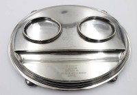 Auktion 376<br>ovale, versilberte Schreibtischgarnitur beziehungsweise ein Doppel-Tintenfass (Inkstand) mit einer Gravur auf der vorderen Ablagefl&auml;che.