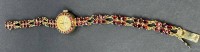 Auktion 376<br>Quartz Damenarmbanduhr "Amara", Norm-Gold-250-, Norm gestempelt, besetzt mit roten Steinen, zusammen 15,36 gr, Werk nicht gepr&uuml;ft
