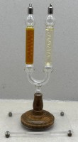 Auktion 376<br>Gei&szlig;lerr&ouml;hre, eine U-f&ouml;rmige Gasentladungsr&ouml;hre oder Fluoreszenzr&ouml;hre mit Holzstand, auf Acrylplatte, H-27 cm, Platte 15x10 cm