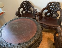 Los 15521 <br>massiver Tisch mit 3 schweren Armlehnstühlen, wohl China, beschnitzt mit Drachen, Alters-und Gebrauchsspuren, Tisch H-77cm D-90cm, Stühle ca. H-92cm B-72cm Sh-46cm.