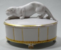 Konfektdose mit Goldstaffage und Raubkatzenfigur, H. 11,5 cm, L. 15 cm, Goldfarbe stellenweise abgerieben, Reparaturstellen am Schwanz der Katze, Boden mit Nummer