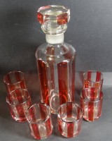 Auktion 332 / Los 10037 <br>Karaffe mit 6 Bechern, rot-klar gestreift, mit Etikett, 1 Becher Rand mit Chip, Karaffe H-26cm Gläser H-7,2cm.