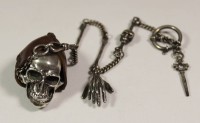 Taschenuhr/Schädeluhr, Craig Compton, in Form eines Schädels, aufklappbar, innen das Uhrwerk, Schädeldeckel dekoriert mit Sonne und Schwan, Uhrenkette mit Memento Mori Elementen und Uhrenschlüssel, Kette punziert Sterling, Kopf wohl Sterling, Schädel in Lederhülle, Werk lose und läuft nur ganz kurz an, Schädel 4,5 x 2,5cm, ohne Werk ca. 72,3gr..