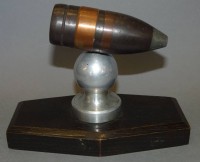 Auktion 339 / Los 7019 <br>Geschosshülse als Paperweight, Holzsockel, H-10 cm, L-17 cm