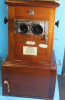 Los 16030 <br>gr. Mentor Spiegelreflex-Stereo Studiokammera "Le Taxiphote" in Mahagoni-Holzgehäuse mit Beschreibung, in Gehäuse unten abschliessbare Tür mit ca. 200-300 Glasplatten mit Stereo-Aufnahmen, um 1890, alles sehr gut erhalten, H. 50 cm, L. 28 cm, T. 28 cm