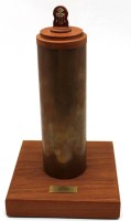 Auktion 342 / Los 15038 <br>massive Messingkartusche auf Holzstand, innen Flasche Asbach, 0,35 L., "Zum Abschied aus dem aktiven Feuerwehrdienst...dat 1989", H-