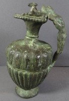 Auktion 344 / Los 15034 <br>Bronze-Krug mit figürlichen Griff, Rand mit zwei Schafböcken, einmal fehlt Kopf, steht etwas nach hinten geneigt, H-18 cm,  Alters-u. Gebrauchsspuren