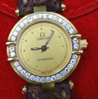 Auktion 355 / Los 2050 <br>Damen-Armbanduhr, Omega Constellation, 750er Gelbgold, Modell Manhatten Chronometer, Lünette mit Brillantbesatz, Quartzwerk, zus. 21gr., Lederband, D-2,2cm