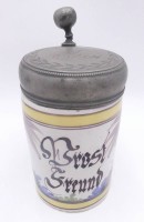 Auktion 360 / Los 9012 <br>Fayence Walzenkrug mit Spruch "Prost Freund"  Zinndeckel mit Monogramm, um 1800, gut erhalten, H-23 cm