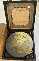 Auktion 363 / Los 16025 <br>Spieluhr "Symphonion" in Holzkasten,ca. 16x16 cm  anbei Holzkasten mit 29 Blechplatten, D-15 cm, Werk steht??