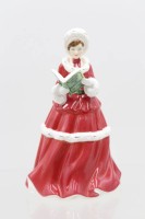 Auktion 366<br>Royal Doulton, "THE TWELVE DAYS OF CHRISTMAS, Frau in winterlichem dunkelrotem Kleid u. Pelzmütze m. Liederbuch, H-16,5cm