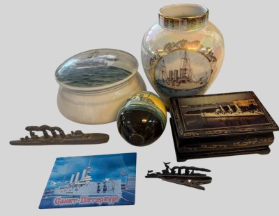 Auktion 373<br>kl. Lot Aurora, dem russ. Panzerdeckkreuzer, der angebl. 1917 in St.Petersburg mit dem ersten Schuss die Oktoberrevolution ausgelöst hat. 2 Bleischiffe, 1 Holzdose, 1 handbemaltes Holzei, Vase und Deckeldose aus Porzellan, 1 kl. Blechschild, zurzeit Nationaldenkmal [1]
