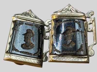 Auktion 375<br>2 Schalclips oder ähnliches in Bierkrugform, Front schwarzer Stein mit griechischen Kriegerkopf, 1x gebrochen, Altersspuren, je ca. 2,5x2 cm [1]