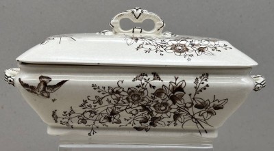 Auktion 375<br>antike, cremefarbene Gemüseterrine aus Steingut mit Deckel und braunem Transferdruck-Blumen- und Vogelmuster im Ästhetizismus-Stil aus dem 19. Jahrhundert, H-13 cm, 29x17 cm, Ecke Deckel Unterseite mit Chip [1]