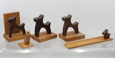 Auktion 376<br>ein Set aus handgeschnitzten Holzfiguren und Wohnaccessoires im Stil eines Terriers (Mid-Century Folk Art / Art Deco), darunter Buchstützen, einen kleinen Stifte- oder Kerzenhalter, ein längeres Schälchen/Ablagebrett und kleine Hunde-Dekorfiguren aus dunklem und hellem Massivholz. [1]