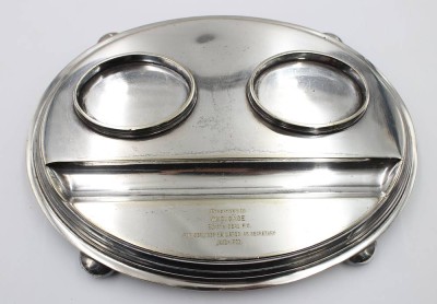 Auktion 376<br>ovale, versilberte Schreibtischgarnitur beziehungsweise ein Doppel-Tintenfass (Inkstand) mit einer Gravur auf der vorderen Ablagefläche. [1]