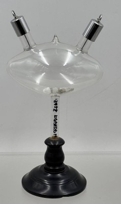 Auktion 376<br>historische  Crookes-Röhre mit phosphoreszierenden Mineralsubstanzen auf Holzstand, Anfang 20.Jhd., H-23 cm [1]