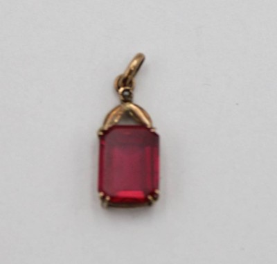 Auktion <br>Anhänger, Gold um 14ct (gepr.), roter Farbstein, zus. ca. 1gr., L-1,5cm B-0,7cm. [1]