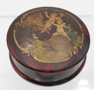 Auktion 348<br> Lackdose, wohl um 1900, Putti-Darstellung, H-4cm D-11,5cm [1]