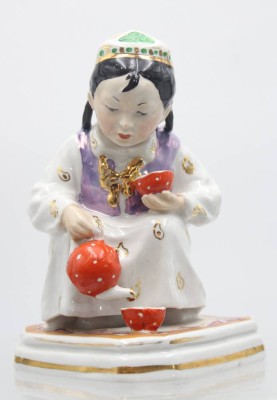 Auktion 357<br>Kleine Gastgeberin Porzellan, Emailbemalung, Lüsterdekor, Vergoldung,  Figur eines hockenden usbekischen Mädchens, Tee ausschenkend, wohl Dulevo-Fabrik, Modell von Olga Michailowna Bogdanowa 1952, H-14cm, kl. Chip an Stand [1]