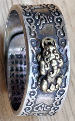 Auktion 358<br>Fingerreif, Silber-990- mit Gold-Ganesha, umlaufend indisches Sonnenrad Symbol, Innenseite der Schiene fas vollstädnig in Hindi? beschriftet, offen, RG ca. 67, 7,8 gr [1]