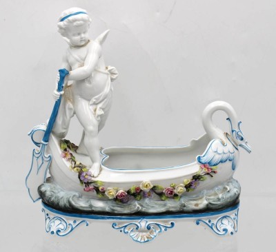 Auktion 362<br>figürliche Schale, Putto als Gondoliere, Déposé gemarkt, teilw. farbig staffiert, aufgesetzte Blüten (einige mit Chips), leider am Kopf geklebt, H-24cm B-24cm [1]