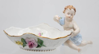 Auktion 363<br>Saliere mit Putto, Sächsische Porzellanmanufaktur Dresden,bunt staffiert, 22 x 11 cm, unterglasurblaue Marke [1]