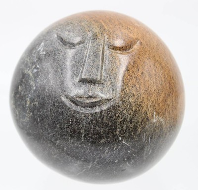 Auktion 364<br>schwere Steinkugel mit Gesicht, wohl Serpentine aus Simbabwe?, signiert Herald M., D-12 cm [1]