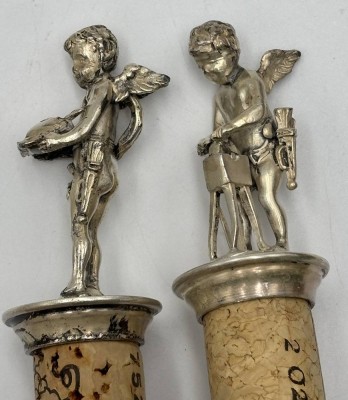 Auktion 364<br>2 Korkenhalter, Putti, versilbert, 1x fehlt ein Flügel, H-ca. 6 cm [1]