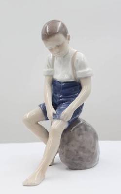 Auktion 367<br>Junge auf Stein sitzend, Bing & Gröndahl, am Sockel monogr. IPI, Entw. Ingeborg Plockross Irminger, Modelnr. 1757, Unterglasurbemalung, H -20cm [1]