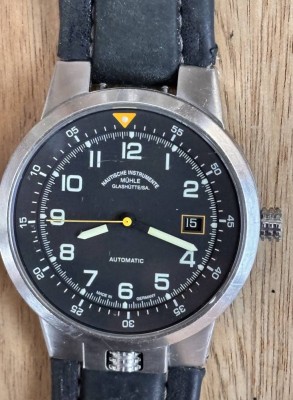 Auktion 369<br>Mühle Glashütte Lufthansa Drei Zeiger. Lufthansa Edfition, Gehäuse aus Edelstahl mit Lederarmband. Saphirglas. Verschraubte Bandanstöße. Ein verschraubter Glasboden gibt den Blick auf das veredelte Werk frei. Wasserdicht bis 10 atm. Gehäusedurchmesser ohne Krone ca. 42mm. Leuchtzahlen und Zeiger. Minuten-Skalaring-Einstellung mittels Stellkrone auf 6 Uhr. Referenz M1 35-33, guter Zustand [1]