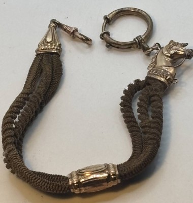 Auktion 370<br>Biedermeier Uhrenkette aus Frauenhaar mit Double (Schaumgold?) Applikationen, Pferdekopf, Mittelstück beidseitig mit verschiedenen Monogramme, 1x dat. 1903, L-ca. 25 cm [1]