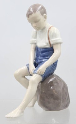 Auktion 370<br>Junge auf Stein sitzend, Bing und Gröndahl, am Sockel monogr. IPI, Entw. Ingeborg Plockross Irminger, Modelnr. 1757, Unterglasurbemalung, H- 19,5cm [1]