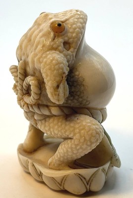 Auktion 370<br>japanische Netsuke, 20.Jhd., Frosch als Sumo-Ringer, auf Lotusblüte stehend, Teganuss signiert, H-5,5 cm, rechte Hand fehlt [1]