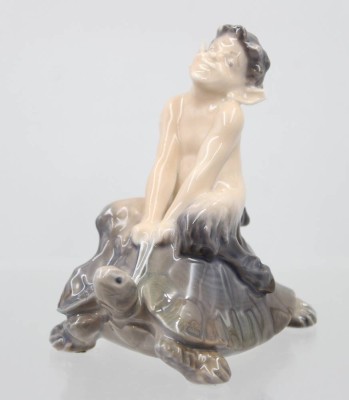 Auktion 373<br>Faun auf einer Schildkröte reitend, Royal Copenhagen, Modellnr. 858, Entw. Christian Thomsen , polychrom bemalt in Unterglasurfarben, H-10cm, am Ohr bestossen [1]